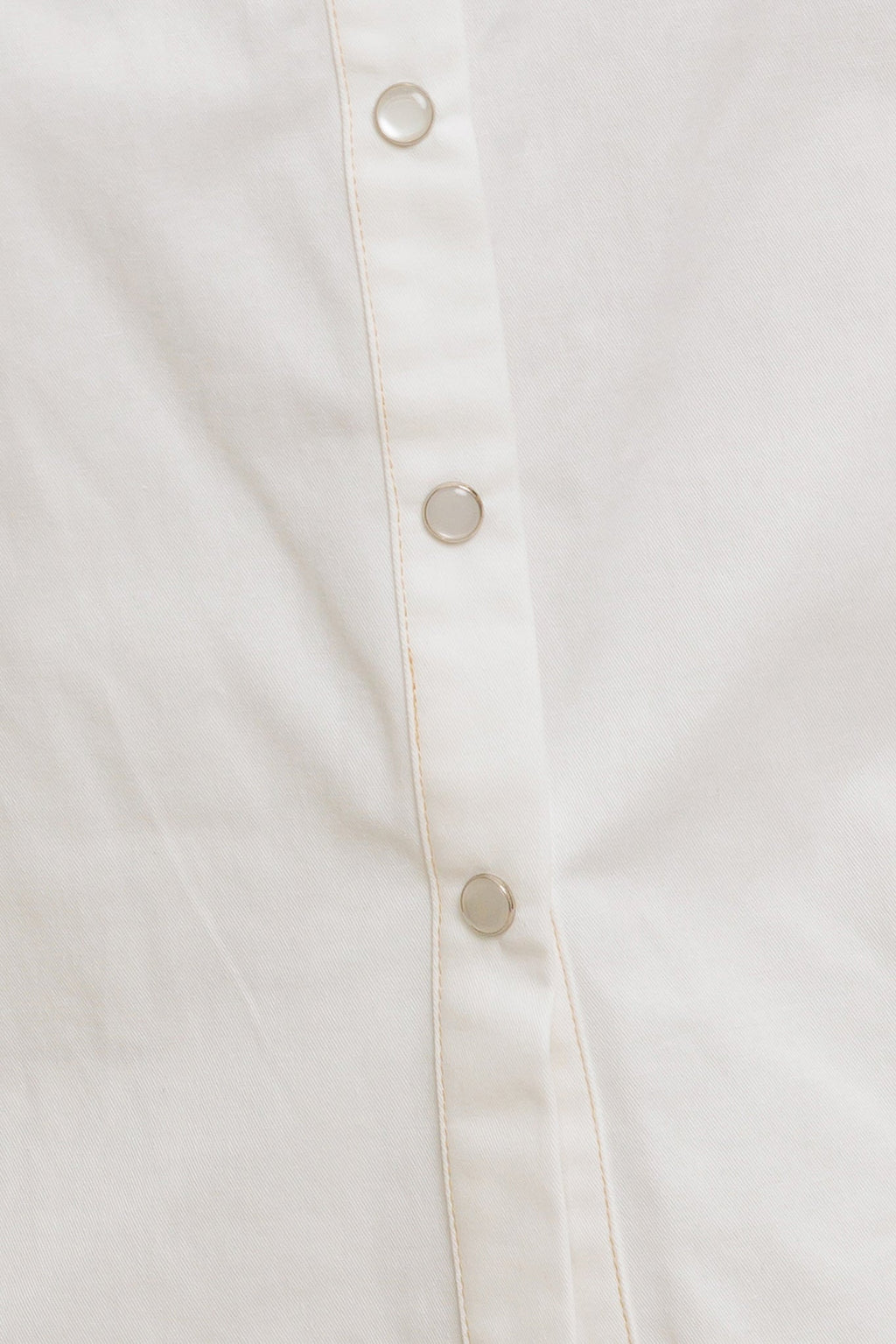 A solid white woven top featuring collar, snap button down, ruffled shoulder, short puff sleeve and pockets