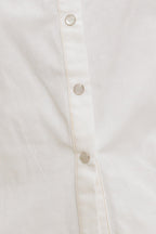 A solid white woven top featuring collar, snap button down, ruffled shoulder, short puff sleeve and pockets
