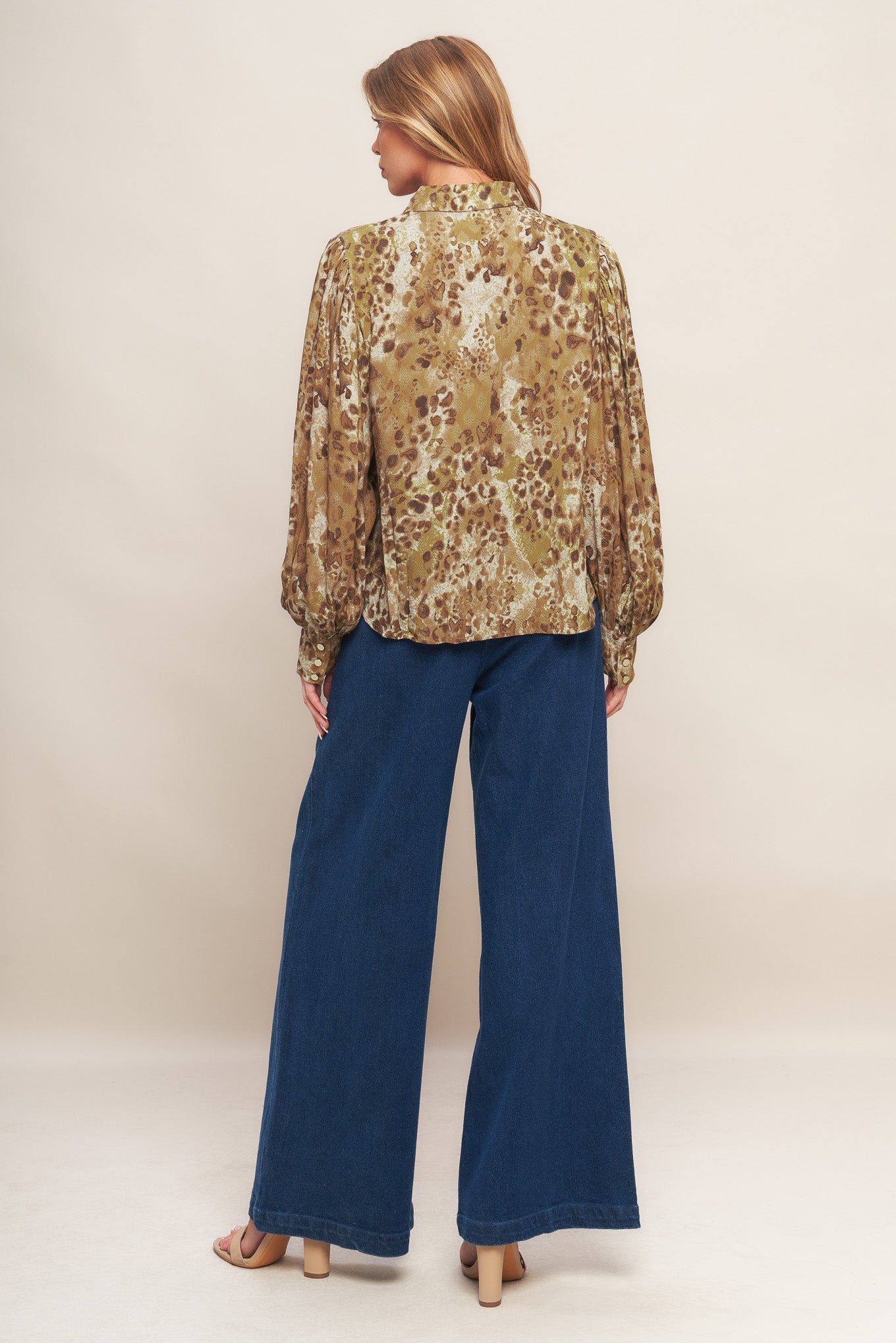 An animal printed woven top featuring collar, front button down and long blouson sleeve with cuff