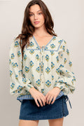 A printed woven top featuring V neckline with tie, yoke and long sleeve with smocked cuff