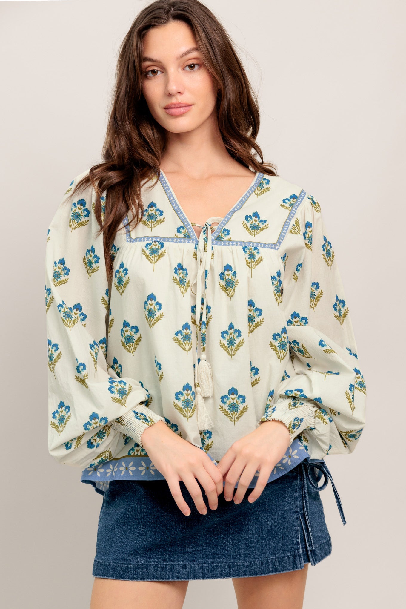A printed woven top featuring V neckline with tie, yoke and long sleeve with smocked cuff