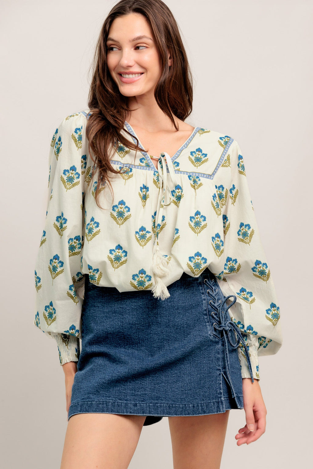 A printed woven top featuring V neckline with tie, yoke and long sleeve with smocked cuff