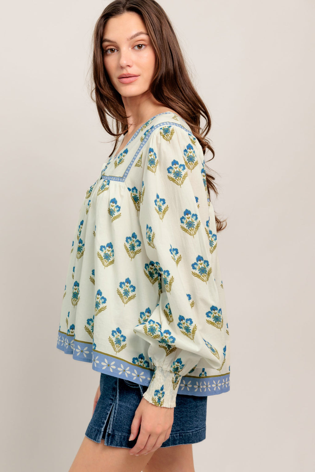 A printed woven top featuring V neckline with tie, yoke and long sleeve with smocked cuff