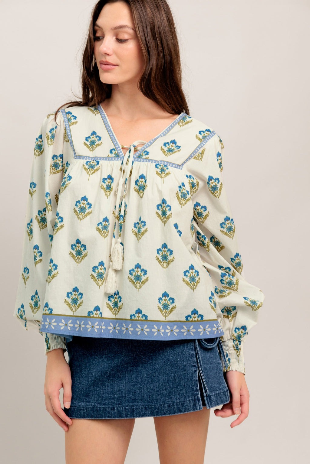 A printed woven top featuring V neckline with tie, yoke and long sleeve with smocked cuff