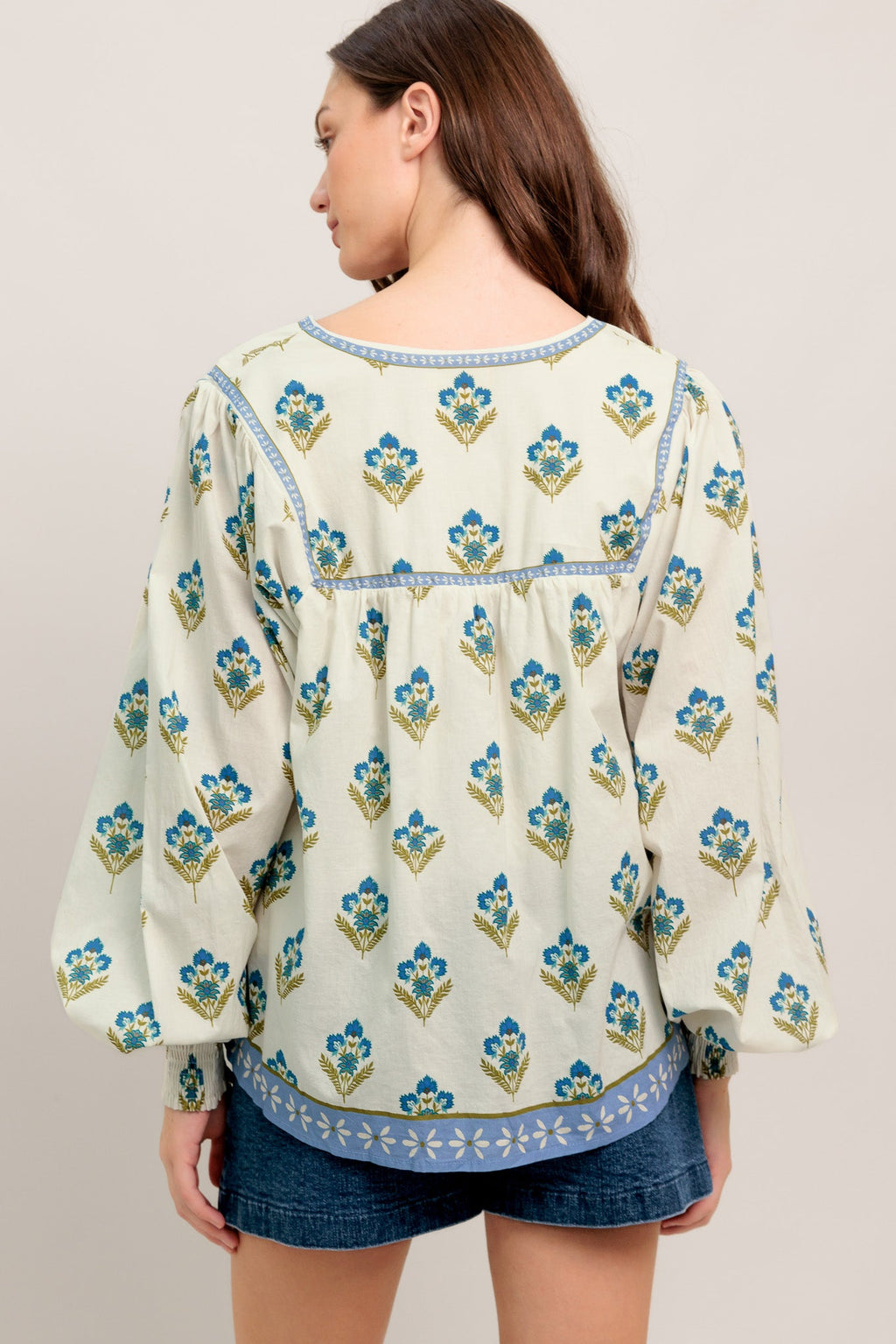 A printed woven top featuring V neckline with tie, yoke and long sleeve with smocked cuff