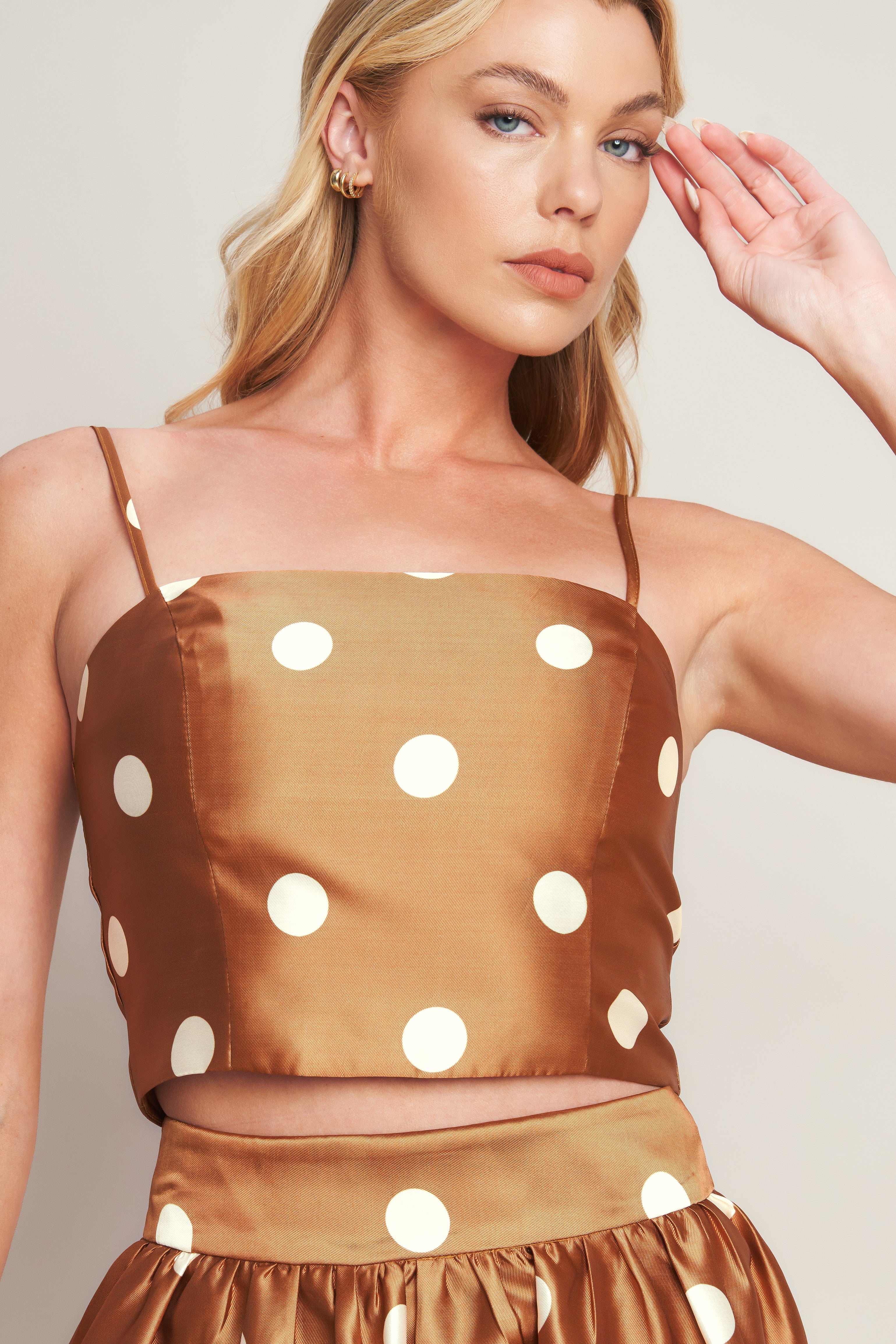 A printed woven polka dot top featuring straight neckline, straps and back zipper closure.