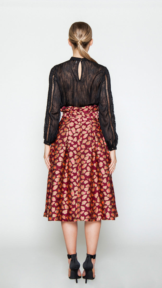 A midi skirt featuring an A-line silhouette, front and back pleats, high paper-bag waistline, side pockets, concealed back zipper closure, optional belt, lined skirt, and cheetah print design