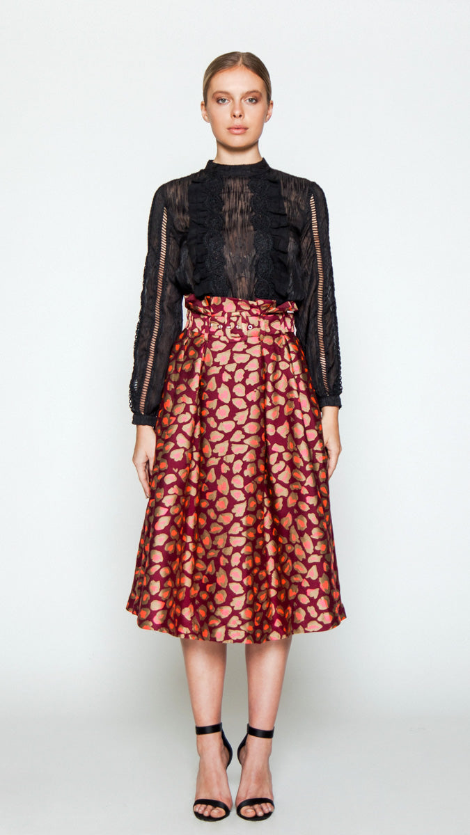 A midi skirt featuring an A-line silhouette, front and back pleats, high paper-bag waistline, side pockets, concealed back zipper closure, optional belt, lined skirt, and cheetah print design