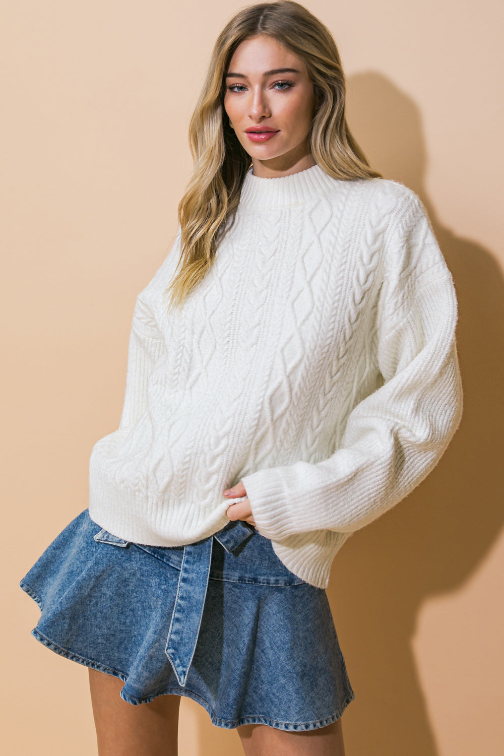 A white knit sweater top featuring mock neck, long sleeve and relaxed body