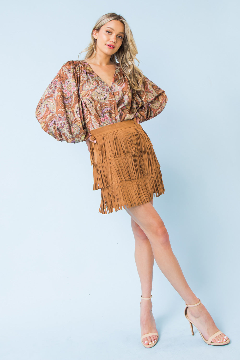 A faux suede mini skirt featuring three layers of fringe and a side zipper closure for a secure fit.