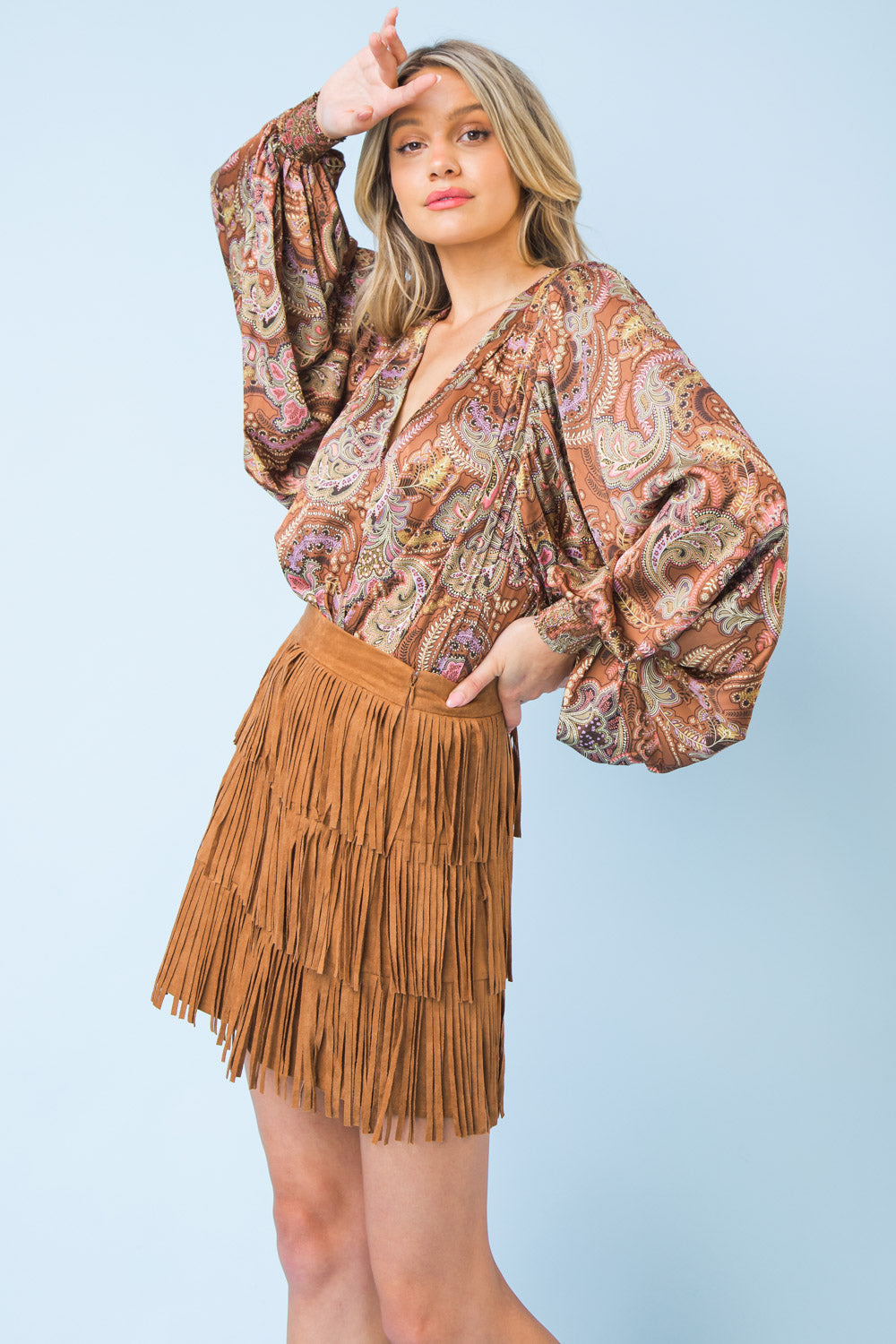 A faux suede mini skirt featuring three layers of fringe and a side zipper closure for a secure fit.